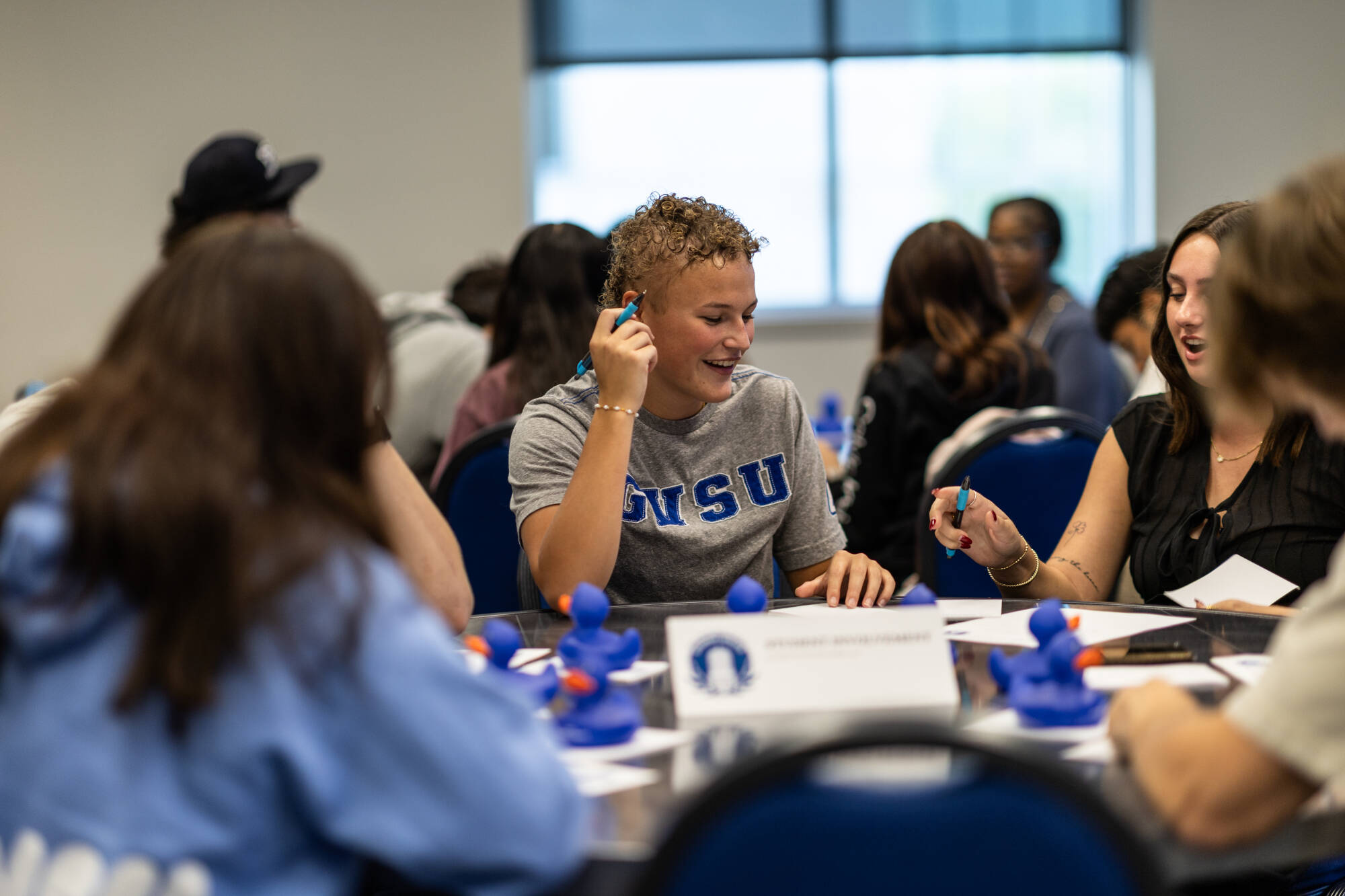 Senators sitting around a table wearing GVSU shirts and talking.
